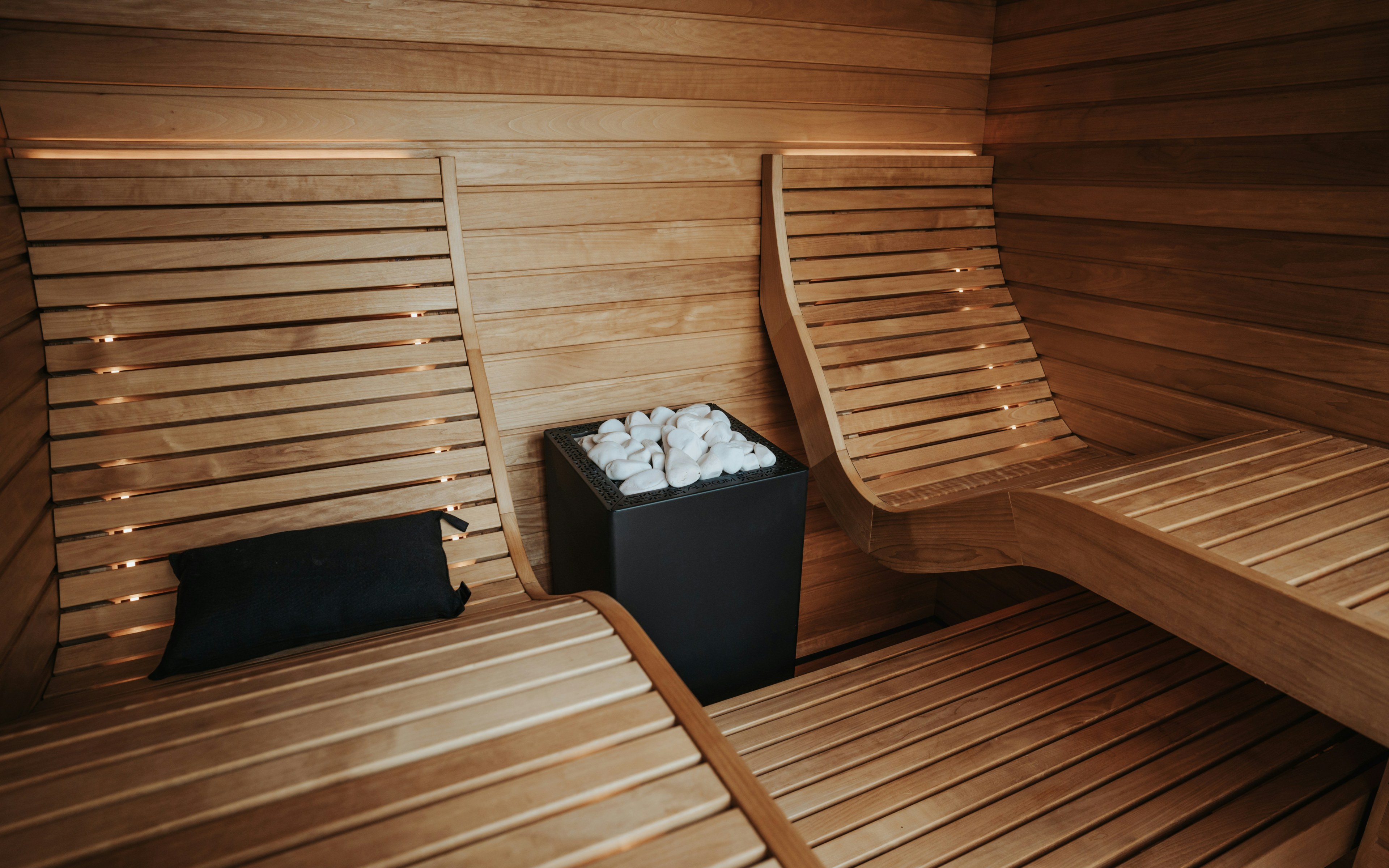 Intérieur de sauna moderne en bois avec bancs et poêle, conçu pour la détente et le rajeunissement de la peau.