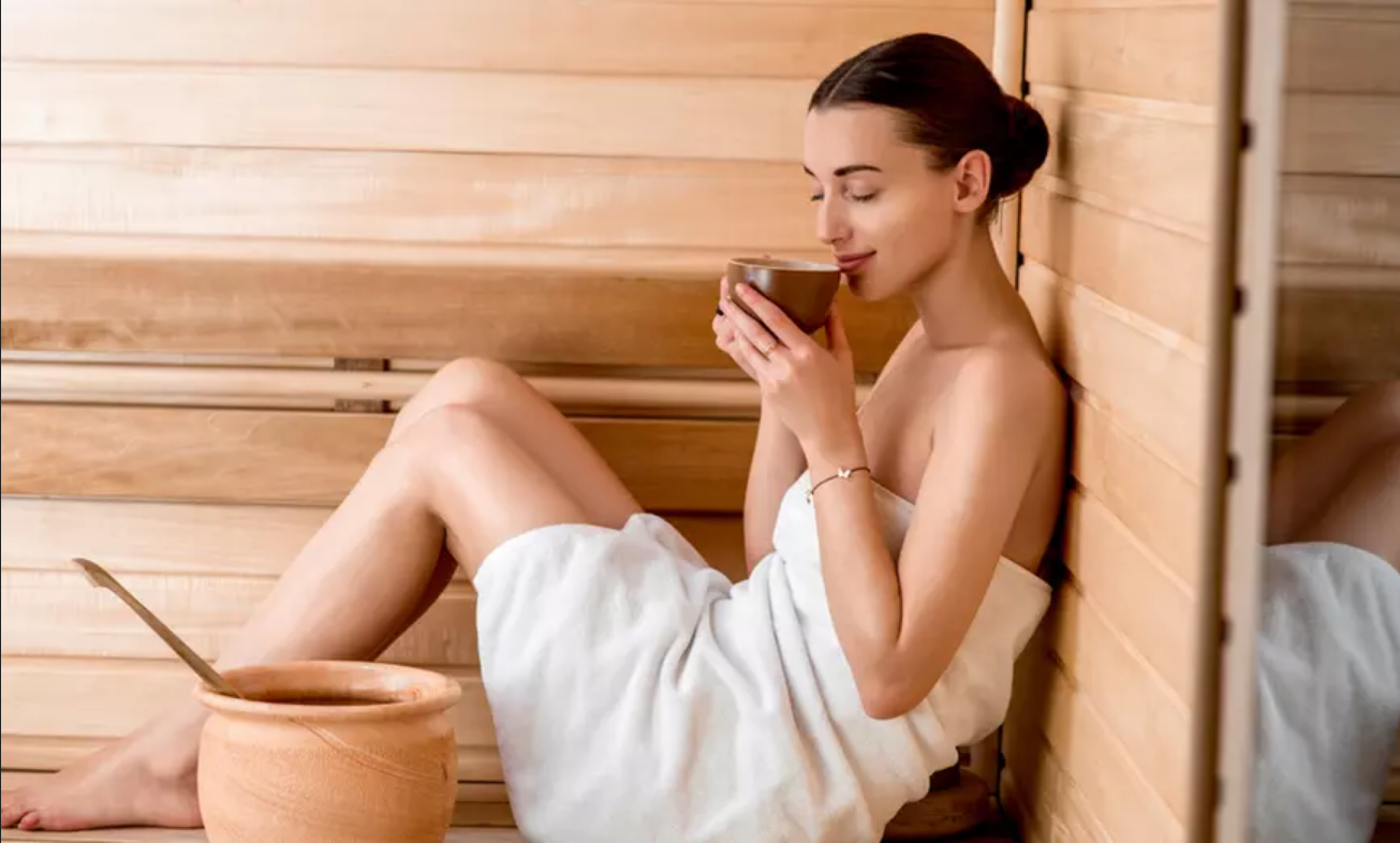 Une femme boit du thé dans un sauna
