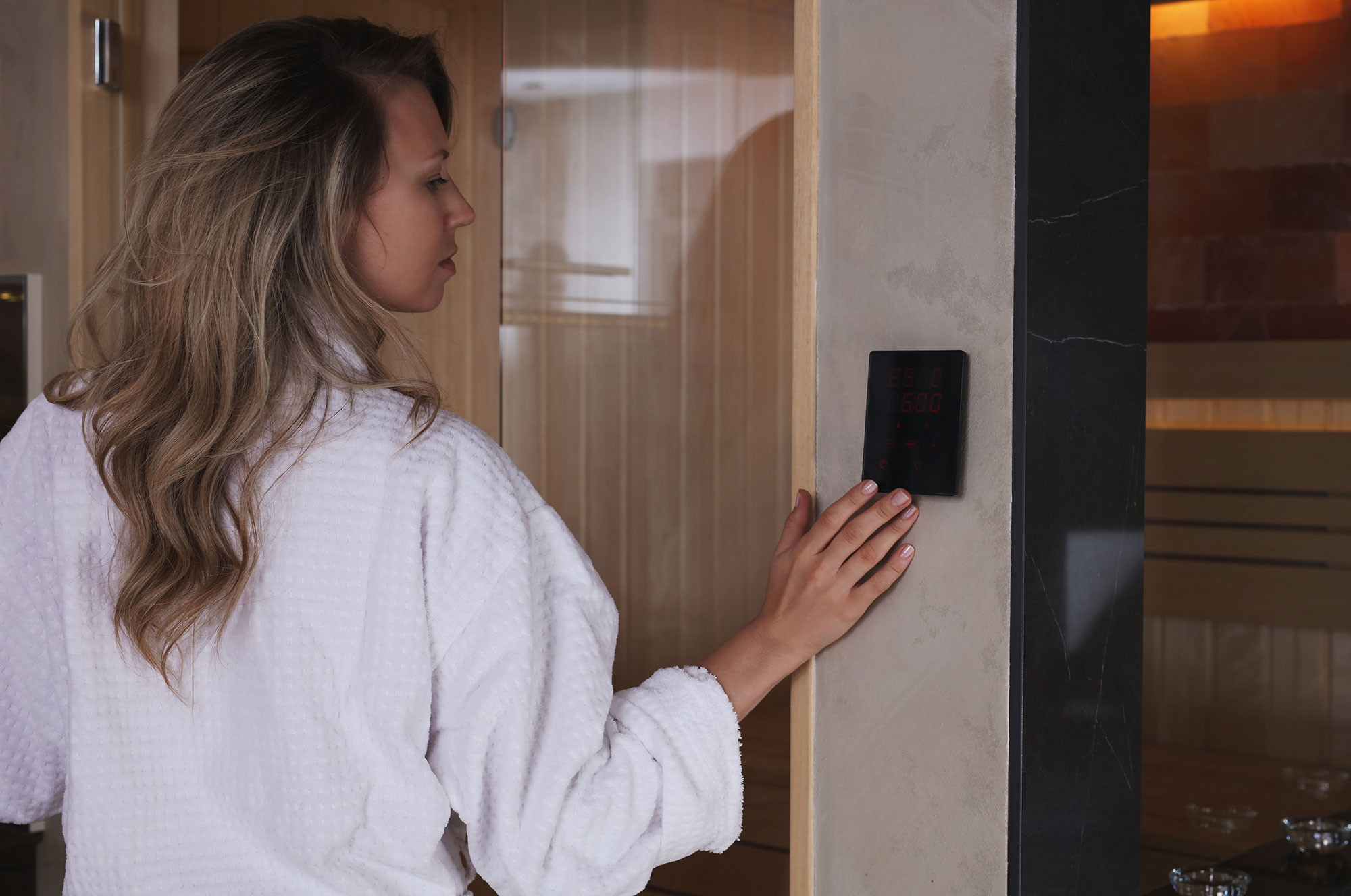une femme règle le panneau de commande du sauna