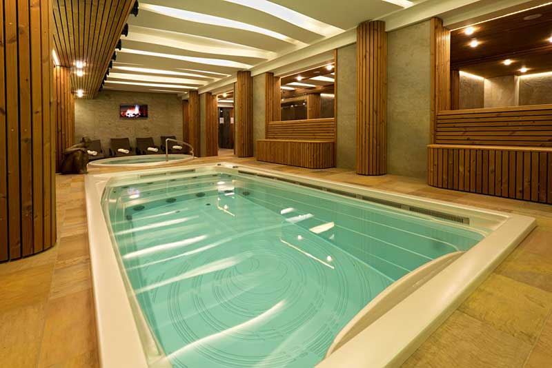 Spa de nage intérieur USSPA installé dans un espace bien-être avec une zone de relaxation séparée