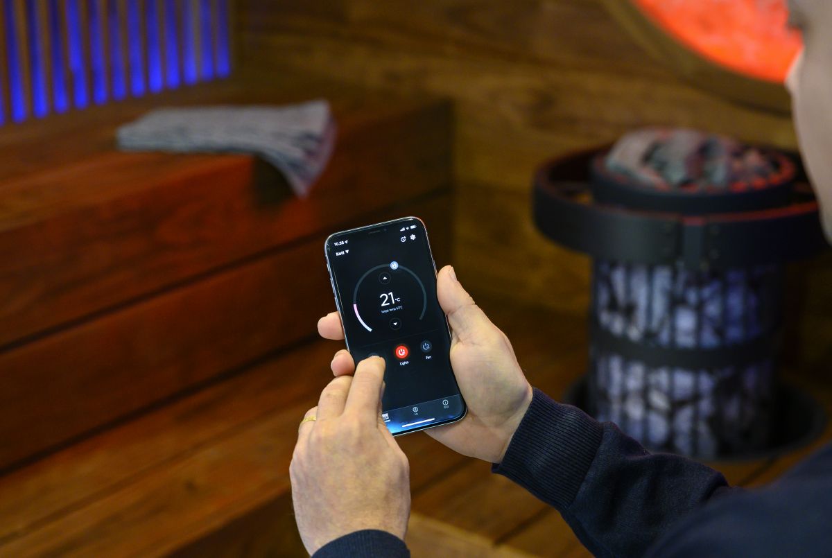 personne contrôlant l'équipement du sauna avec l'application mobile MyHarvia