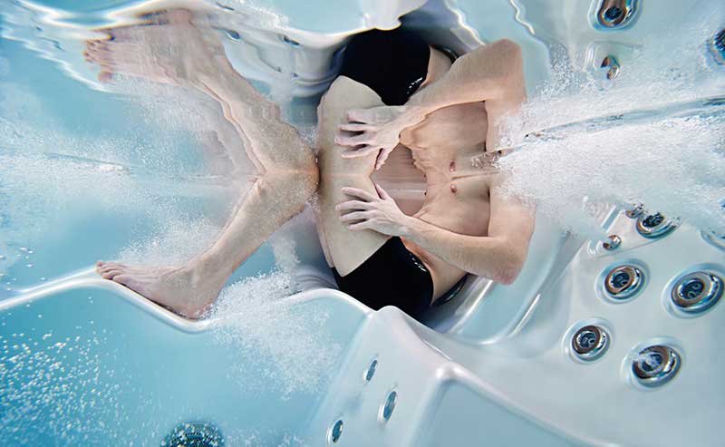 Femme se détendant sur une chaise longue ergonomique d'un spa USSPA avec jets d'hydromassage en marche
