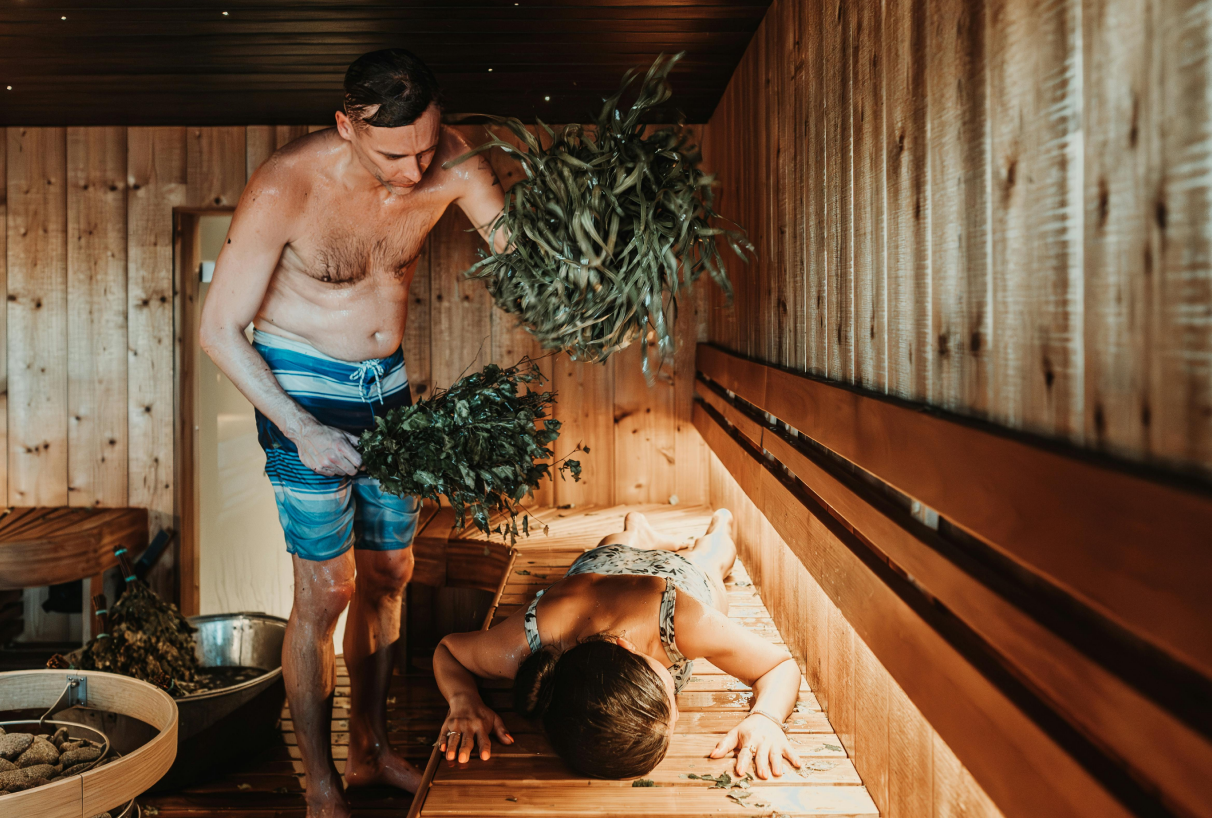 Un homme frappe une femme avec un fouet en bouleau dans le sauna – un rituel traditionnel de détente.